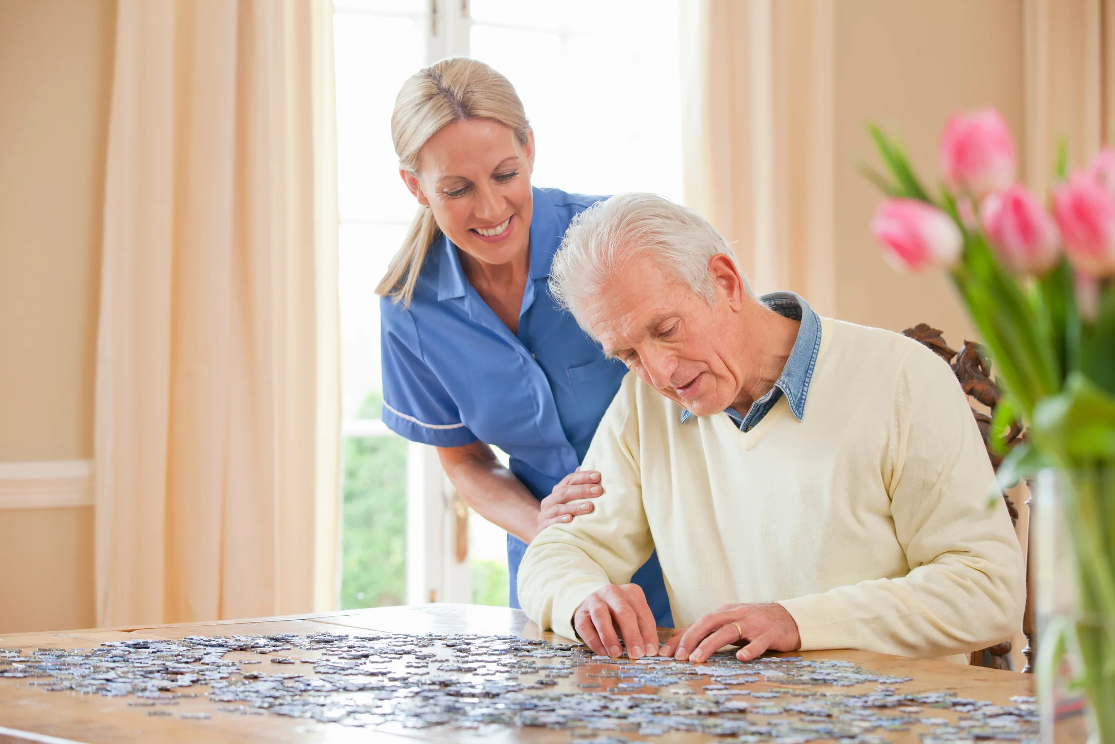 Caregiver and older adult working on a jigsaw puzzle together