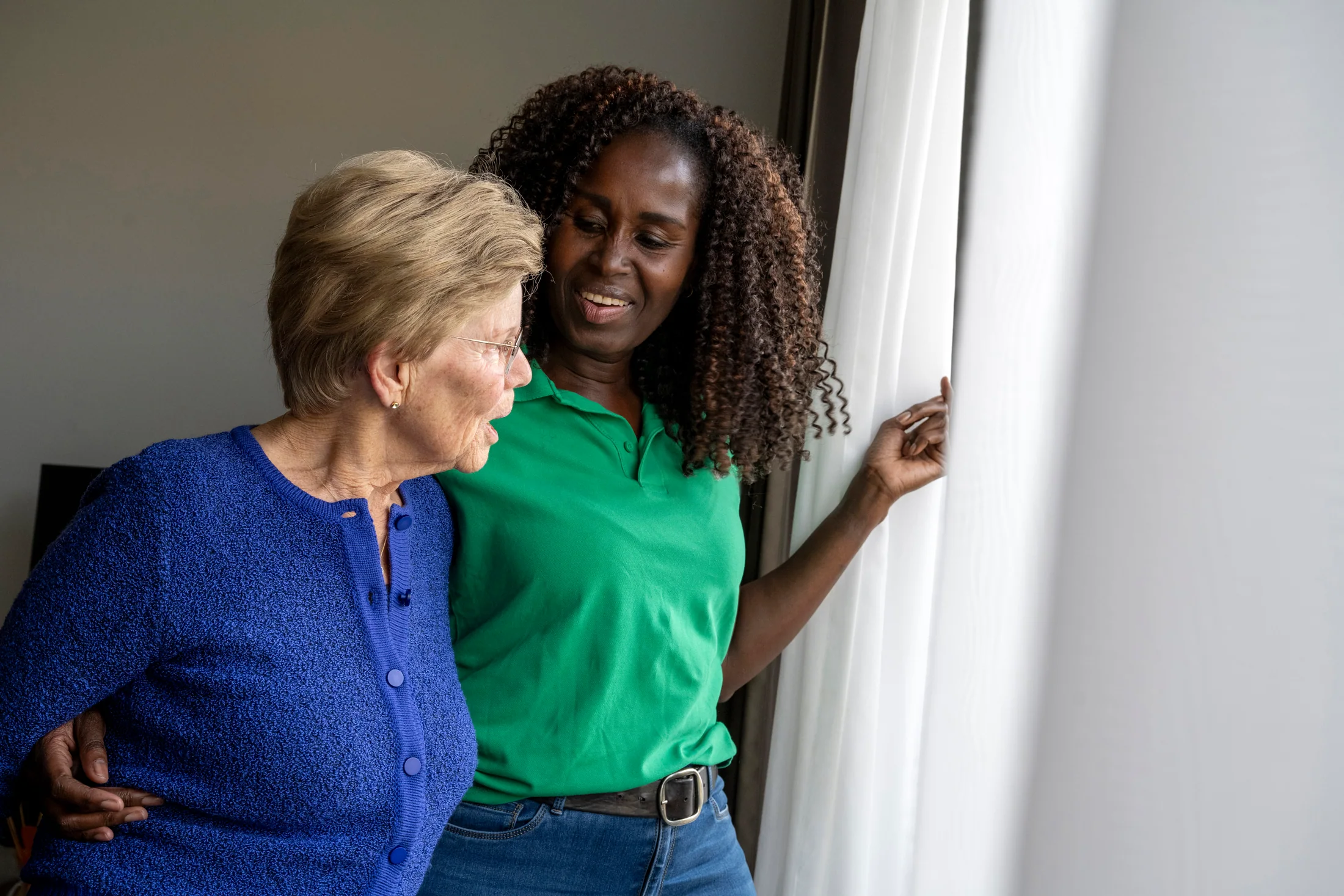 Caregiver and older adult sharing a conversation beside a window