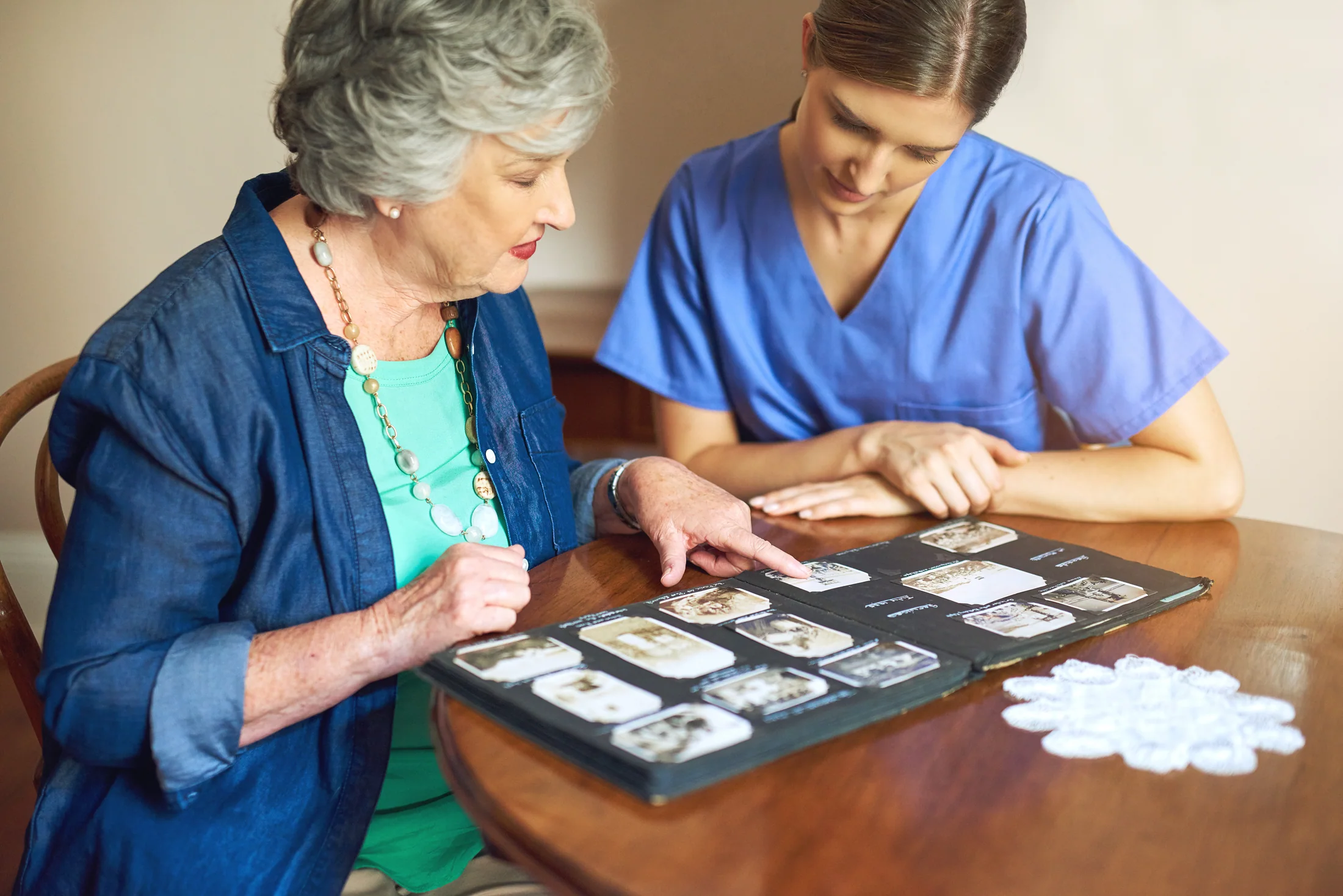 Older woman and caregiver looking through family photographs together