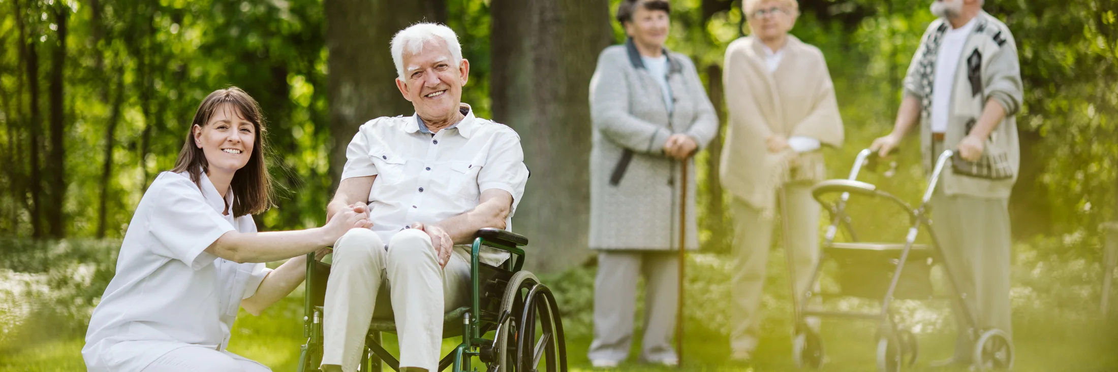Caregiver accompanying an older man who uses a wheelchair outdoors