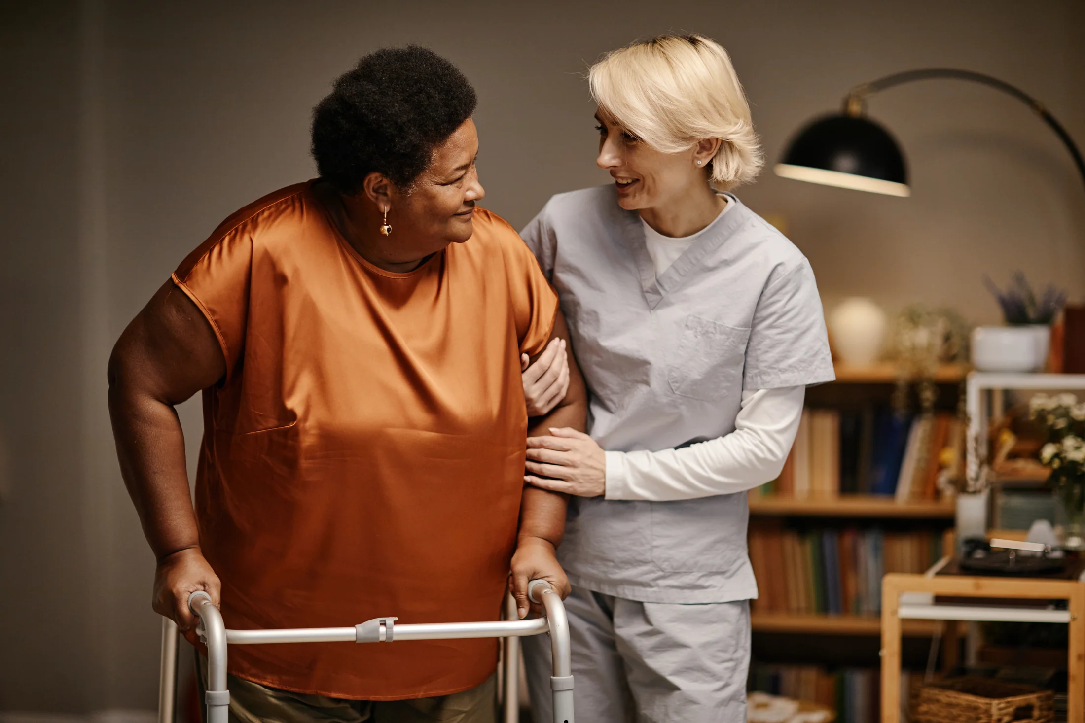 Caregiver assisting an older adult who is using a walker at home
