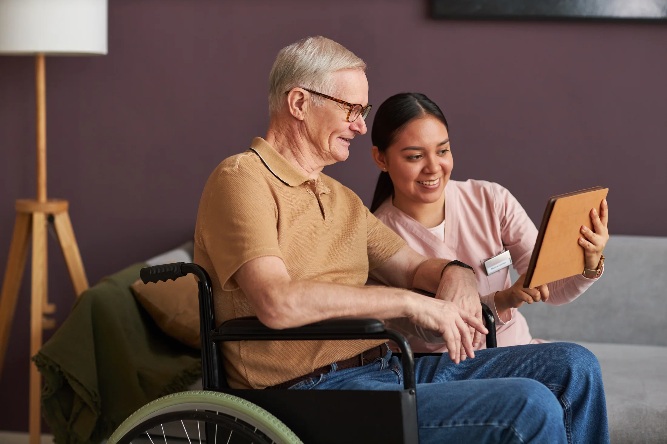 Caregiver helping an older man use a tablet